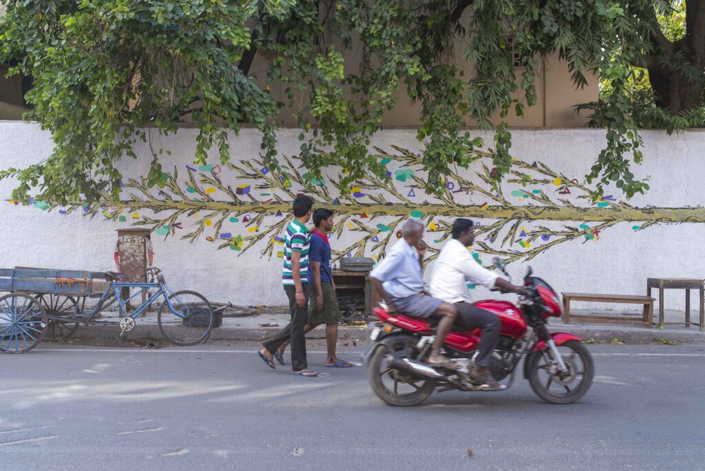 Persons walking and biking in front of a mural